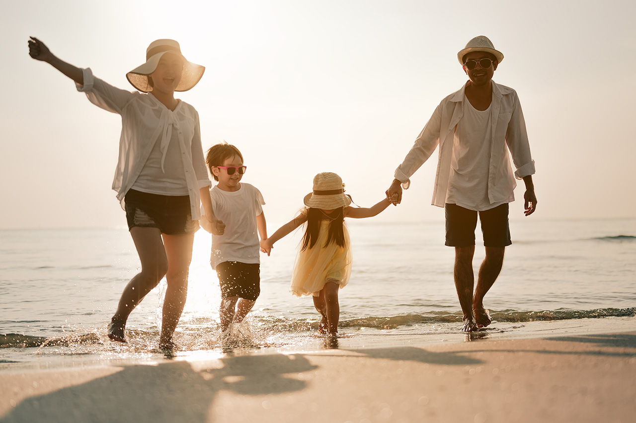 Smiling family walking hand in hand on the beach, enjoying a leisurely stroll.